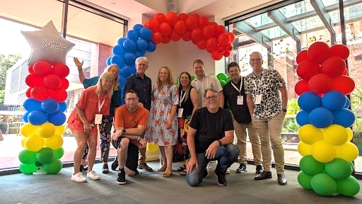 A group of people in front of a balloon display of the letter G.